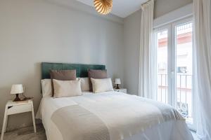 biała sypialnia z dużym łóżkiem i oknem w obiekcie Guadalquivir Terrace Suite Apartments w Sewilli
