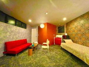 ヴィラ犬山 في إينوياما: غرفة معيشة مع أريكة حمراء وسرير