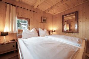 a bedroom with a large white bed with a mirror at Bergspektive - Haus Alpenspa in Rieding