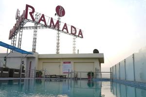 una piscina con un cartel en la parte superior de un edificio en Ramada by Wyndham Jalandhar City Center en Jalandhar