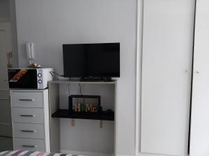 a room with a tv on a stand with a microwave at ESTUDIO EMMA in Torrevieja
