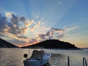 un barco está atracado en el agua al atardecer en Apartmani Kate en Lastovo