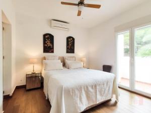 1 dormitorio con 1 cama blanca y ventilador de techo en Casa Armonía, en Benissa
