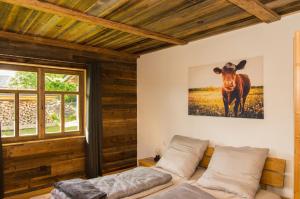 a room with a bed and a picture of a cow at Chalet am Ölberg mit Badefass und Altholzsauna in Waldmünchen