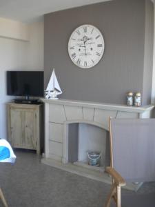 eine Uhr an der Wand über einem Kamin in der Unterkunft Apartment Sandeman in De Panne