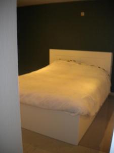 - un lit blanc dans une chambre dotée d'un mur noir dans l'établissement Apartment Sandeman, à La Panne