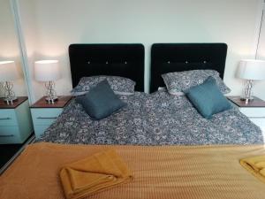 a bed with blue pillows and a black headboard at Carvetii - Walter House - First floor flat sleeps 6 in Leslie
