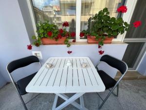 un tavolo bianco con sedie di fronte a una finestra con fiori di Апартамент Иванови a Pomorie