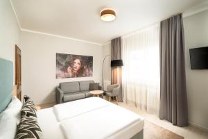 ein Hotelzimmer mit einem weißen Bett und einem Sofa in der Unterkunft Arthotel ANA Eden in Karlsruhe