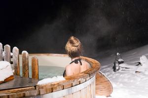 une femme assise dans un bain à remous dans la neige dans l'établissement atipic lodge, à Arette