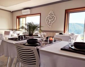 een eetkamer met witte tafels, stoelen en ramen bij Paraiso Do Gabriel 