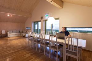 un hombre sentado en una mesa de comedor con un portátil en Russkiy Dom, en Longyearbyen