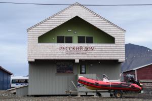 um barco vermelho está estacionado fora de um edifício em Russkiy Dom em Longyearbyen