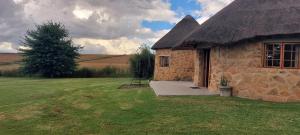 a stone house with a thatched roof in a field at Blackbrook Farm Underberg in Underberg