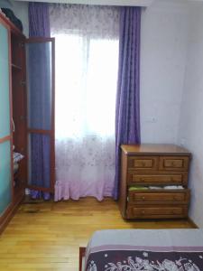 ein Schlafzimmer mit einer Kommode und einem Fenster mit lila Vorhängen in der Unterkunft Apartment On 26 May Str in Batumi