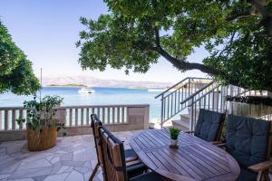 a wooden table and chairs on a patio overlooking the water at Apartments Nikolina in Lumbarda