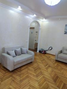 ein Wohnzimmer mit einem weißen Sofa und Holzböden in der Unterkunft Apartment On 26 May Str in Batumi