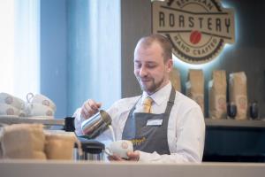 a man in a kitchen preparing food with a spoon at Maldron Hotel Manchester City Centre in Manchester