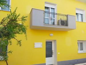 a yellow building with a balcony and a door at Helianthus in Assemini