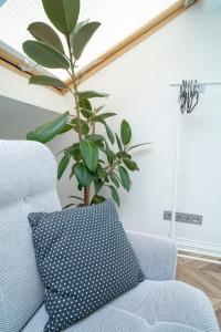 a pillow sitting on a couch next to a plant at House 22A Apartments in Kaunas