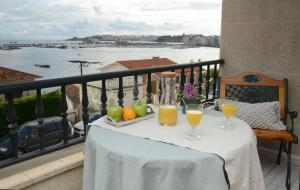einen Tisch mit zwei Gläsern Orangensaft auf dem Balkon in der Unterkunft Desconectaengalicia Mantela, vistas puerto deportivo, 20m Playa in Sanxenxo