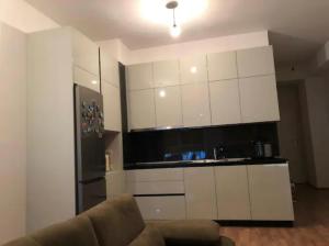 Modern apartment in Tirana في تيرانا: مطبخ مع دواليب بيضاء وثلاجة