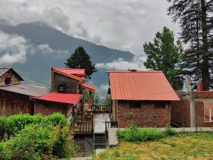 a group of buildings with red roofs and a mountain at The cottage and cheese in Manāli