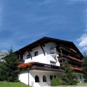 a large white building with flowers on the balcony at Quality Hosts Arlberg - AFOCH FEI - das Landhaus in Sankt Anton am Arlberg