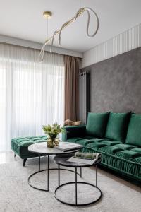a living room with a green couch and two tables at Urbanstay Suites - Prime Location Designer Suite in Bucharest