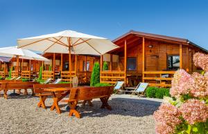 une maison avec bancs et parasols devant elle dans l'établissement Domki 3W Wicie, à Wicie