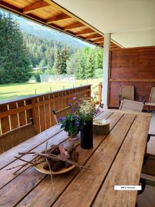 einen Holztisch auf einer Veranda mit Blumen darauf in der Unterkunft Appartement Bel Monte in Bad Kleinkirchheim