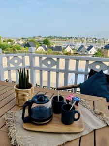 a tea pot and two mugs on a table on a balcony at TY CAÏRN - PORTE DU CROUESTY in Arzon