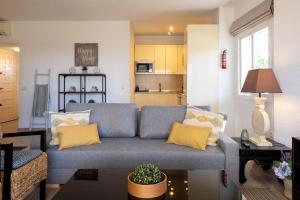 sala de estar con sofá azul y almohadas amarillas en MD001 Precioso Apartamento en Primera Linea de Playa, en Mijas Costa