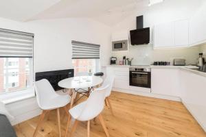 uma cozinha branca com uma mesa e cadeiras brancas em Lovely 1-BDR w/ free parking in central Reading em Reading
