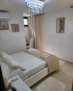 GibaにあるLa Casa Delle Rose 1のベッドとシャンデリアのある白い寝室