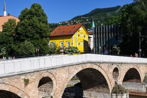 a bridge over a river with a yellow building at Ornament Hotel in Sarajevo