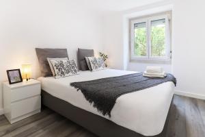 um quarto branco com uma cama grande e uma janela em Belem Boutique Apartments by Homing em Lisboa