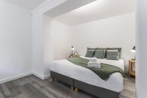 a white bedroom with a large bed with green pillows at Belem Boutique Apartments by Homing in Lisbon