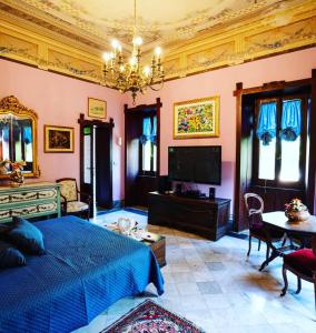 a bedroom with a blue bed and a tv at Villa dei Marchesi Carrozza in Santa Teresa di Riva