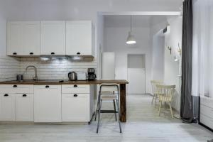 cocina con armarios blancos, mesa y sillas en d.Five Timber Town Apartment, en Budapest