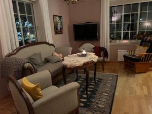 uma sala de estar com uma mesa e cadeiras e uma televisão em Sjarmerende hus med veldig stort uteareal. em Brekstad