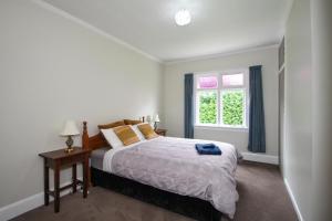 um quarto branco com uma cama e uma janela em Tyne and Tides em Oamaru