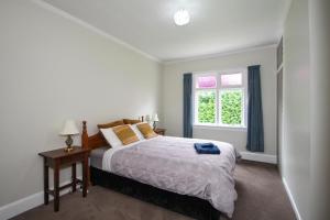 a white bedroom with a bed and a window at Tyne and Tides in Oamaru