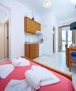 - une chambre avec un lit rouge et des serviettes dans l'établissement Studios Eftihia, à Keratokampos