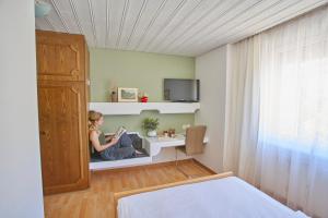 Eine Frau, die in einem Schlafzimmer auf einem Regal sitzt. in der Unterkunft Hotel La Balance self check-in in Biel