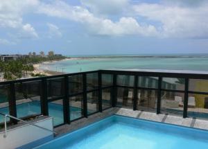 a balcony with a swimming pool and a view of the beach at Beira Mar Apartmento 107 in Maceió