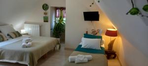 a bedroom with two beds and a chair and a tv at Aux penates de Toni Beauval in Céré-la-Ronde