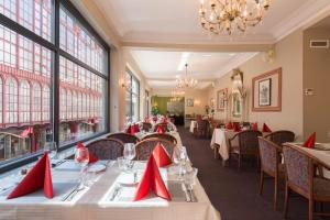 un comedor con mesas y sillas con servilletas rojas en Century Hotel Antwerpen Centrum, en Amberes