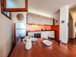a kitchen with a wooden table with chairs and a refrigerator at Trilocale La Pineta Quiet garden in Marina di Campo