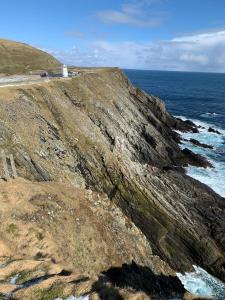 a house on a cliff next to the ocean at Islesburgh House Hostel in Lerwick